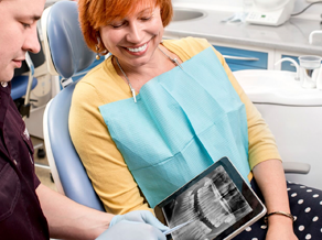 Dentist holding tablet with x-ray image next to patient in chair